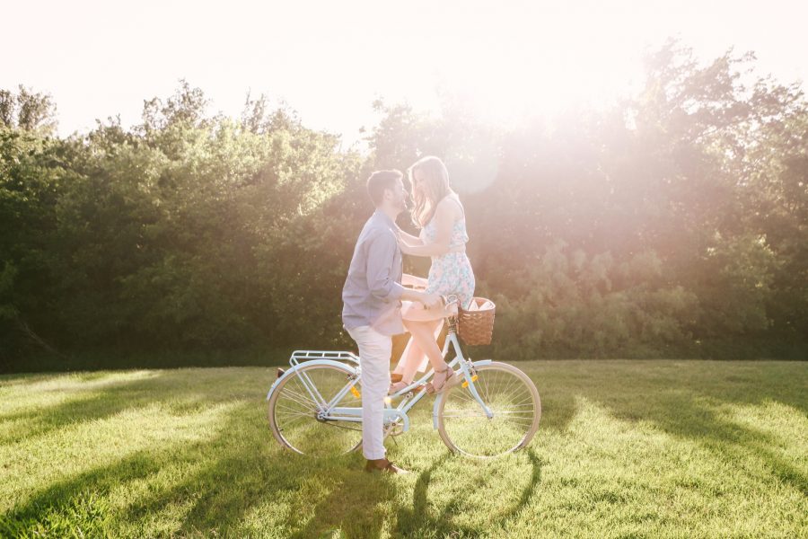 Cole and Caitlin Edwards on a vintage blue bike with a basket during golden hour